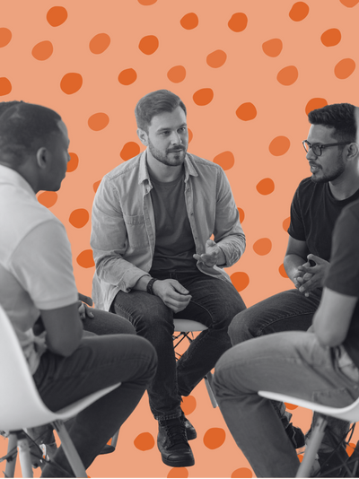 A black and white image of a group of men sitting in a close circle talking to one another.